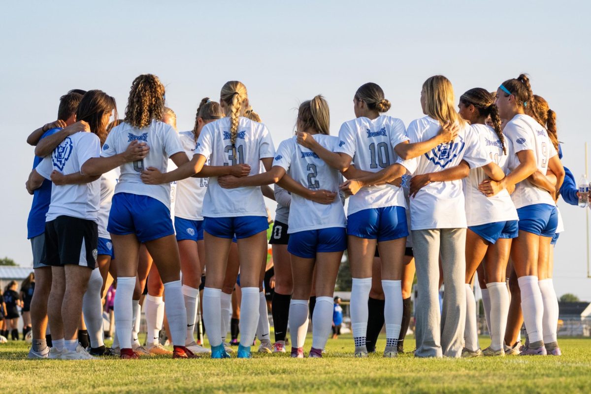 The Lady Royals huddle close as Coach Greg Davidson delivers a pre-game speech.