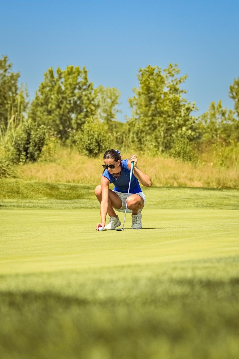 Senior Karolina Franssen lines up her putt at Bear Slide Golf Club.