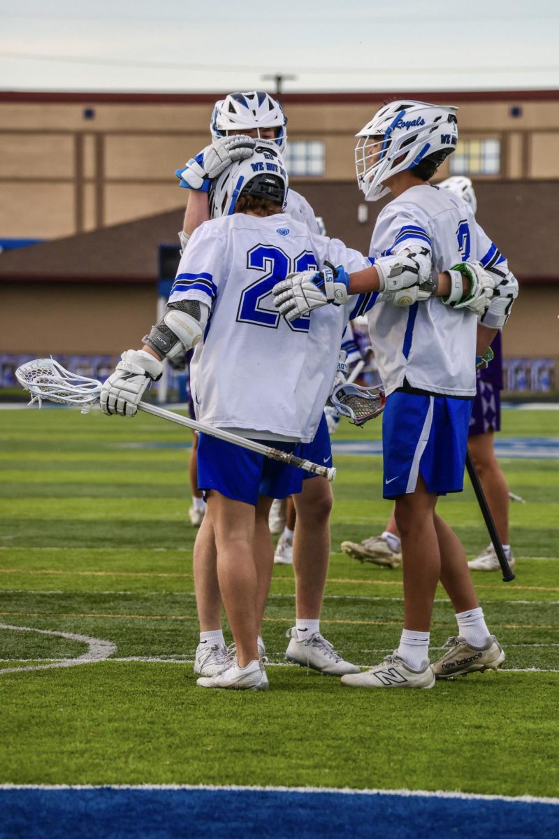 The boys lax team huddles together after scoring.